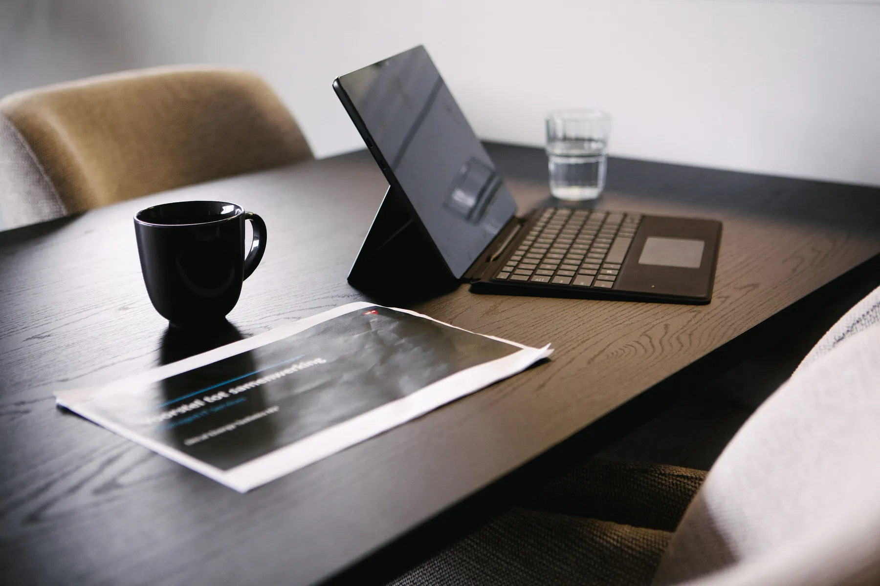 Laptop, koffiemok en waterglas op vergadertafel bij Morow